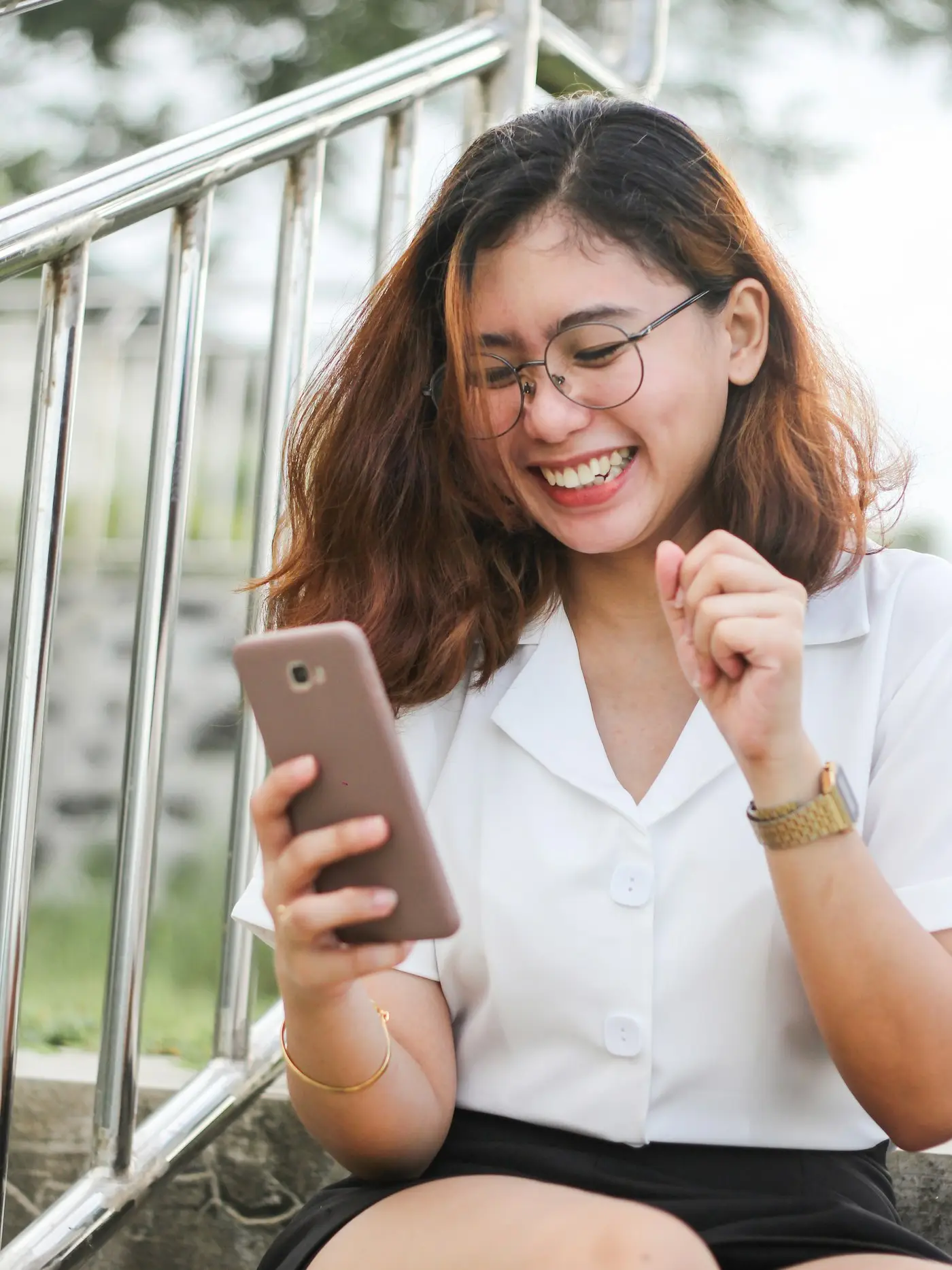 Mulher de óculos sorrindo enquanto usa o celular