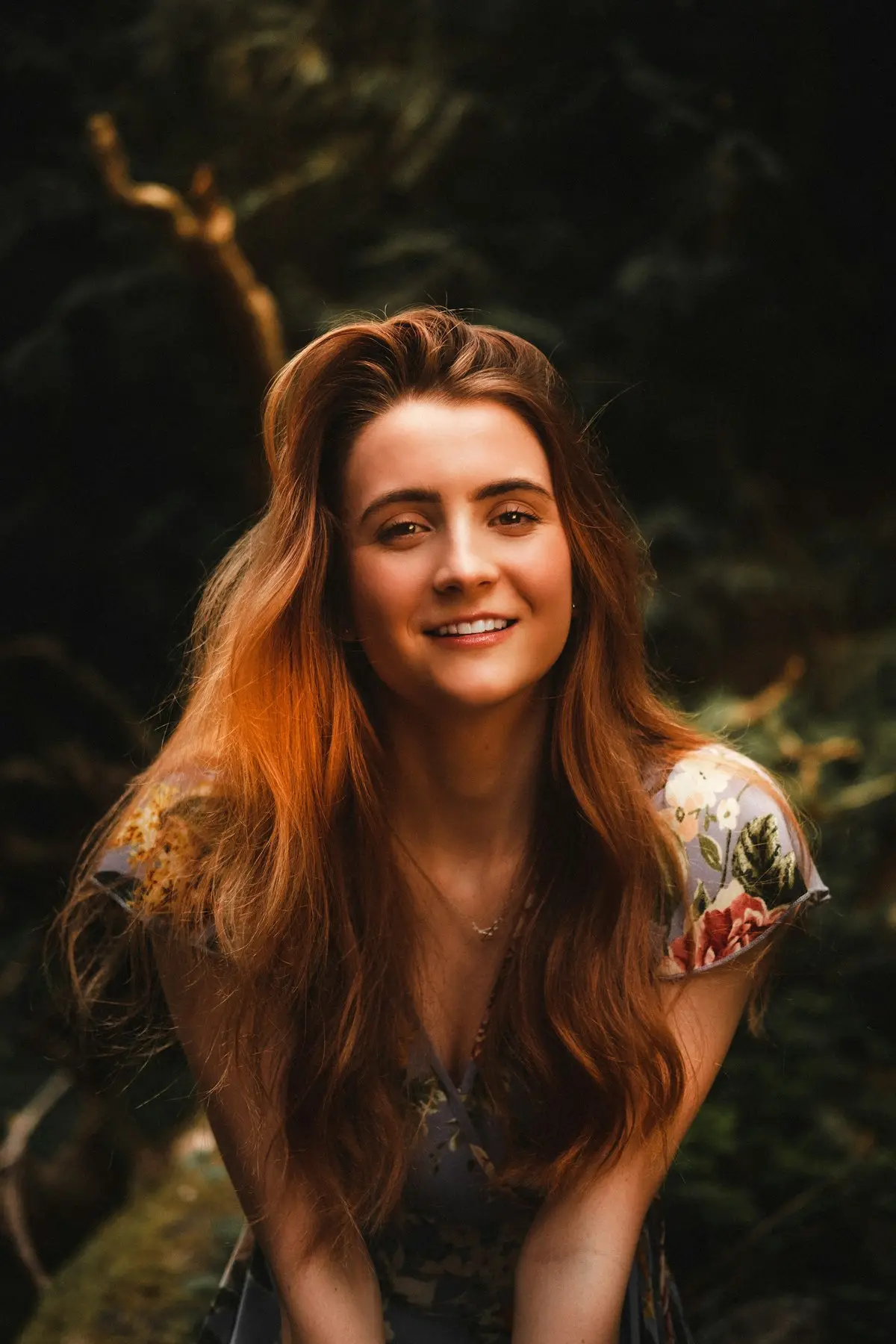 Mulher ruiva de cabelo longo sorrindo, sob luz quente de fim de tarde